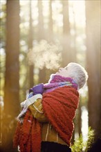 Older Caucasian woman breathing steam outdoors