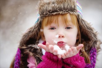 Caucasian girl blowing handful of snow