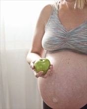Pregnant Caucasian woman holding green apple