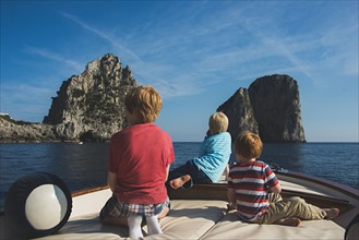 Caucasian brothers on boat admiring rock formations in ocean
