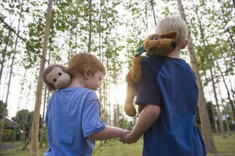 Caucasian brothers carrying stuffed animals outdoors