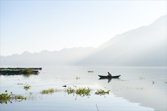 Man rowing canoe on still remote lake