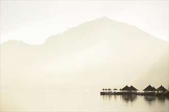 Huts reflecting in still remote lake under mountains