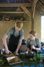 Caucasian brothers cooking in outdoor kitchen