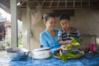 Asian mother and son cooking in outdoor kitchen