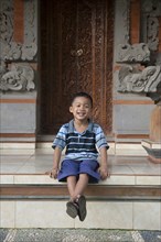Asian boy sitting outside ornate building