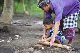 Asian father teaching son traditional wood carving