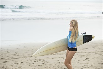 Caucasian surfer carrying surfboard on beach