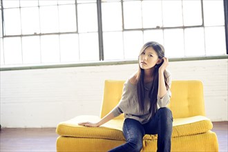 Asian woman sitting on yellow sofa