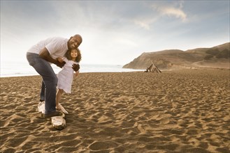 Father and daughter smiling on beach