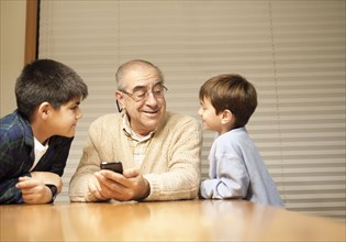 Grandfather and grandsons with cell phone at table