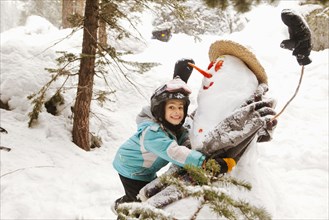 Smiling girl hugging snowman