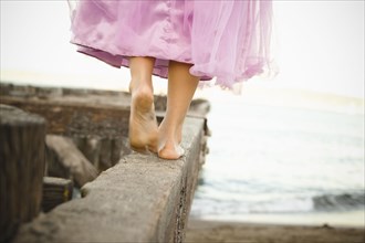 Mixed race girl in costume walking on dilapidated pier