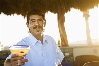 Hispanic bartender serving cocktail