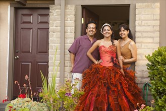 Hispanic girl dressed for quinceanera standing with parents
