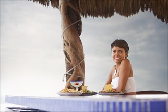 Hispanic woman having dinner at poolside