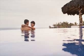 Hispanic couple hugging in swimming pool