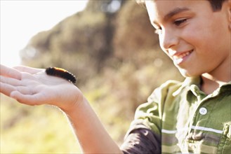 Boy holding caterpillar in his hand
