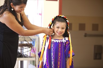 Hispanic mother helping daughter with festive costume