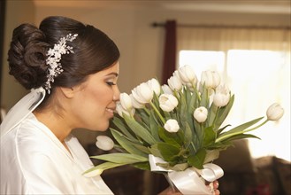 Hispanic bride smelling bouquet