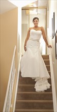 Hispanic bride standing on staircase