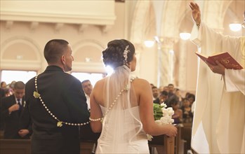 Hispanic bride and groom in wedding ceremony