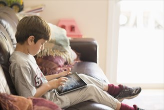 Hispanic boy on sofa using digital tablet