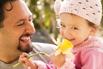 Father smiling at daughter with flower