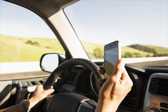 Hispanic woman driving and using cell phone