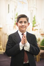 Hispanic boy with hands clasped in church