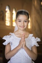 Hispanic girl with hands clasped in church