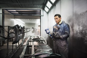 Worker spray painting in manufacturing plant