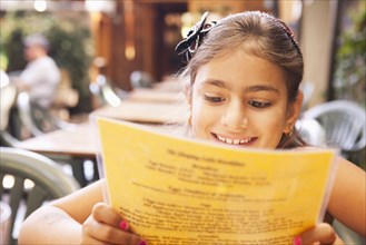 Mixed race girl reading menu in restaurant