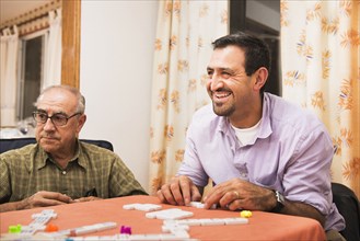 Hispanic men playing dominoes at table