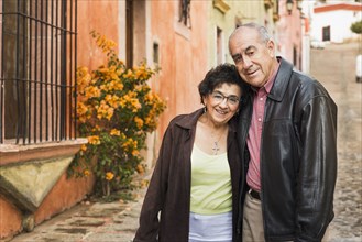 Older Hispanic couple walking on village street