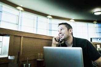 Caucasian man on cell phone using laptop