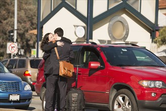 Hispanic couple hugging in parking lot