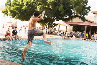 Mixed race boy jumping into pool