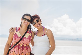 Hispanic women smiling together on beach