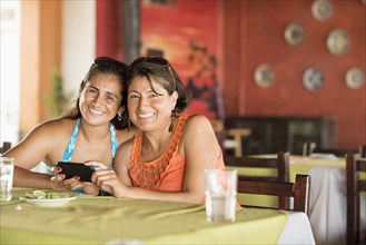 Hispanic women using cell phone at table