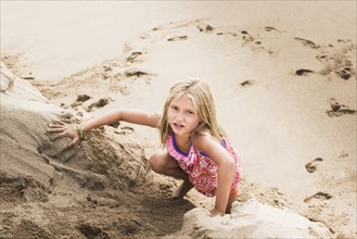 Caucasian girl climbing sand hill on beach