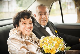 Senior newlywed couple riding in car