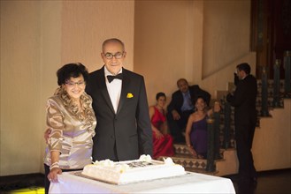 Senior newlywed couple smiling with wedding cake