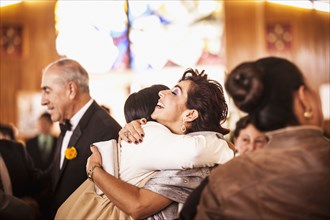 Hispanic family hugging at wedding reception