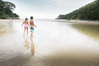 Mixed race children playing in water on beach