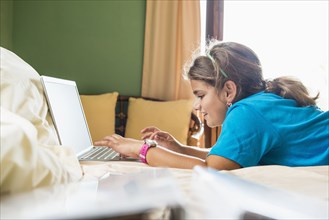 Mixed race girl using laptop on bed