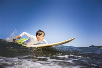 Mixed race boy surfing in ocean