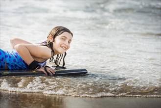 Mixed race girl riding boogie board at beach