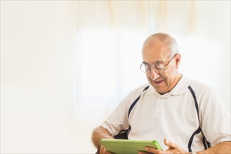 Older Hispanic man using digital tablet