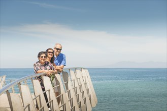 Family smiling together at waterfront railing